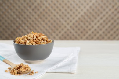 Ceramic bowl with granola on white wooden table, space for text. Cooking utensil