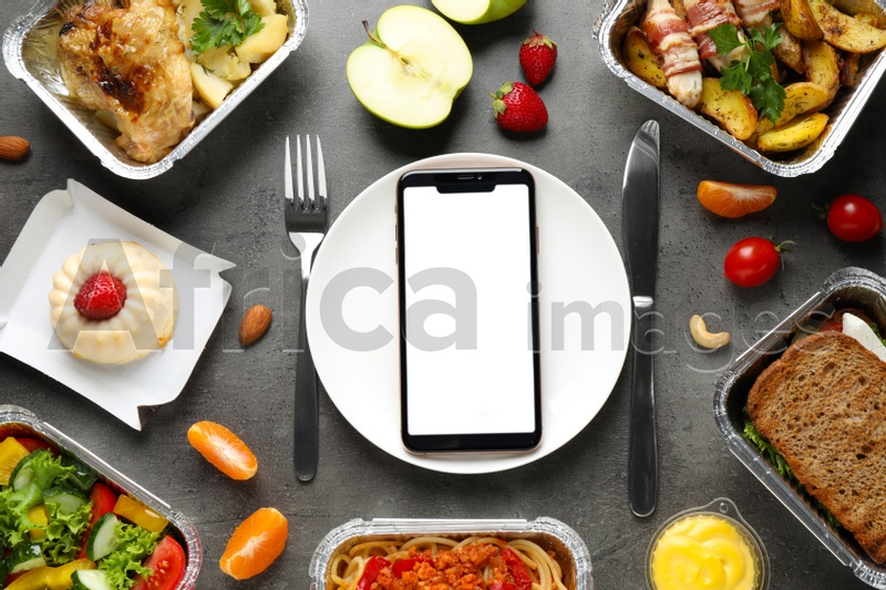 Flat lay composition with lunchboxes and smartphone on grey table, mockup for design. Healthy food delivery