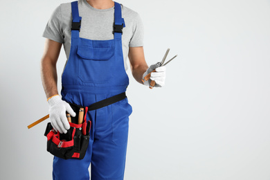 Carpenter with tool belt and chisels on light background, closeup
