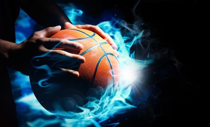 Basketball player with ball in flame on black background, closeup 