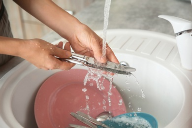 Woman washing dishes in kitchen sink, closeup view. Cleaning chores