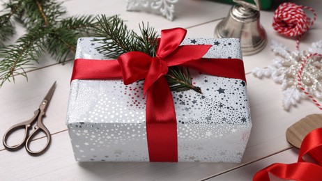 Beautifully wrapped gift box on white wooden table, closeup