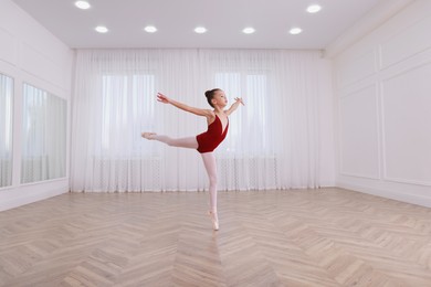 Little ballerina practicing dance moves in studio