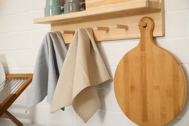 Different towels and wooden board hanging on rack in kitchen