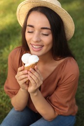 Photo of Happy young woman with delicious ice cream in waffle cone outdoors