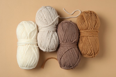Soft woolen yarns on beige background, flat lay