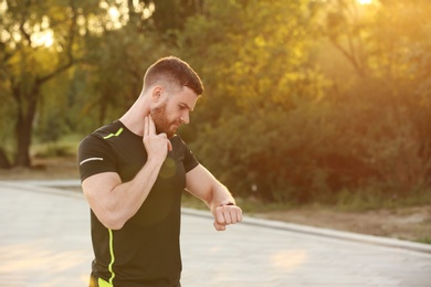 Young man checking pulse after workout in park