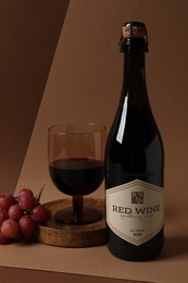 Delicious red wine and grapes on brown background