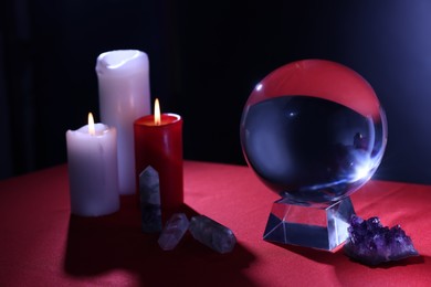 Crystal prediction ball, candles and stones on table in darkness. Fortune telling