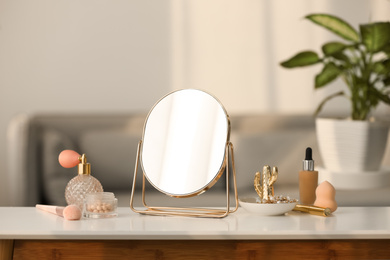 Mirror, jewelry and makeup products on white table indoors