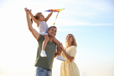 Happy parents with their child playing with kite on beach. Spending time in nature