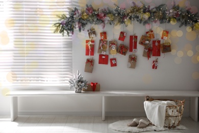 Photo of Christmas Advent calendar with gifts and decor hanging on white wall in room