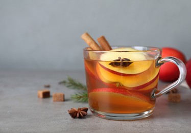 Aromatic hot mulled cider on grey table. Space for text