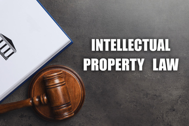 Text Intellectual Property Law, wooden judge's gavel and book on grey background, flat lay