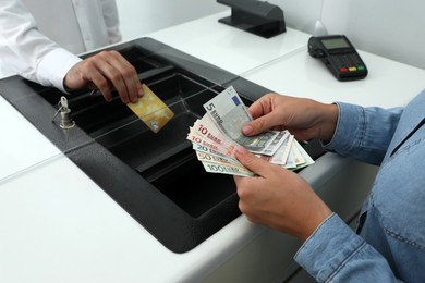Woman taking money from card in bank, closeup. Currency exchange