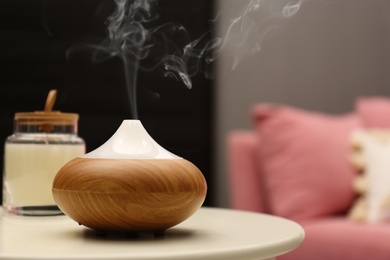 Photo of Aroma oil diffuser on table in room. Space for text