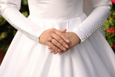 Bride wearing beautiful engagement ring and wedding dress, closeup