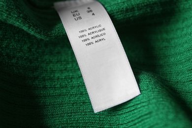 Clothing label with material content on green shirt, closeup view