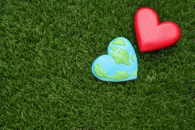 Happy Earth Day. Plasticine planet and decorative heart on green grass, flat lay with space for text