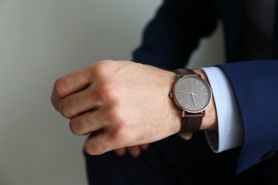 Businessman with luxury wrist watch on grey background, closeup