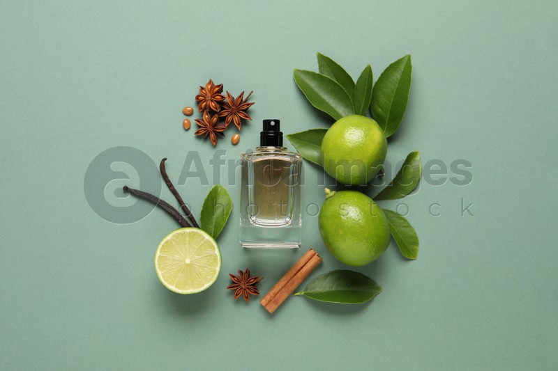 Photo of Flat lay composition with bottle of perfume and fresh citrus fruits on pale green background