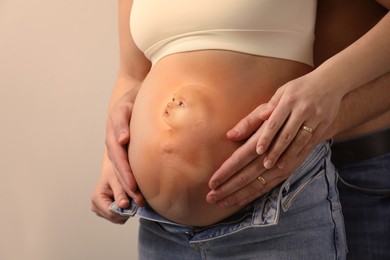 Man, pregnant woman and baby on beige background, closeup view of belly. Double exposure