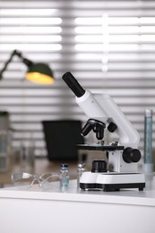 Photo of Modern medical microscope on white table in laboratory