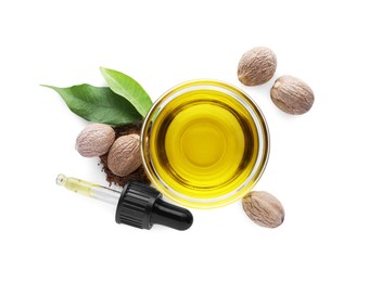 Bowl of nutmeg oil, pipette and nuts on white background, top view