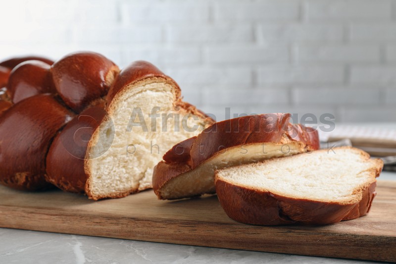 Photo of Cut homemade braided bread on grey table, closeup. Traditional Shabbat challah