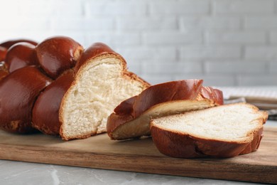 Cut homemade braided bread on grey table, closeup. Traditional Shabbat challah