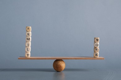 Work family balance concept. Wooden ball with cubes and small plank on grey background