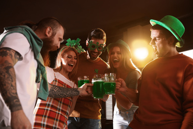 Group of friends toasting with green beer in pub, low angle view. St. Patrick's Day celebration