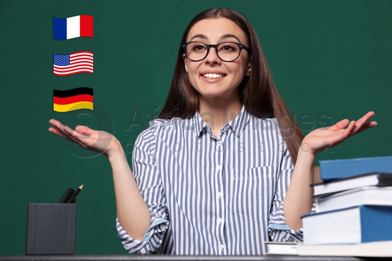 Portrait of foreign languages teacher at table and different flags green chalkboard