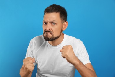 Aggressive man ready to fight on light blue background