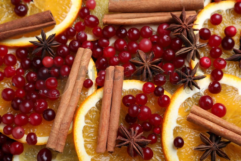 Fresh ripe cranberries, spices and orange slices as background, closeup
