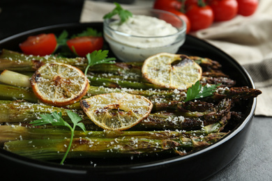 Oven baked asparagus with lemon slices served on plate, closeup