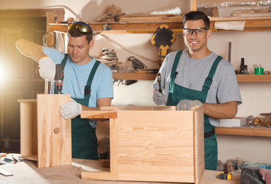 Professional carpenters assembling wooden cabinet in workshop