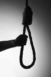 Silhouette of woman holding rope noose on light background, closeup