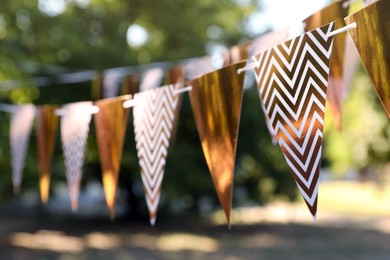 Golden bunting flags in park. Party decor