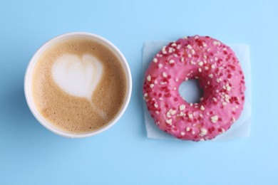 Photo of Tasty frosted donut and cup of coffee on light blue background, flat lay