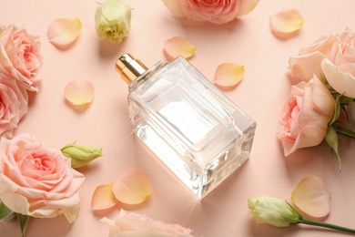 Bottle of perfume, beautiful roses and petals on beige background
