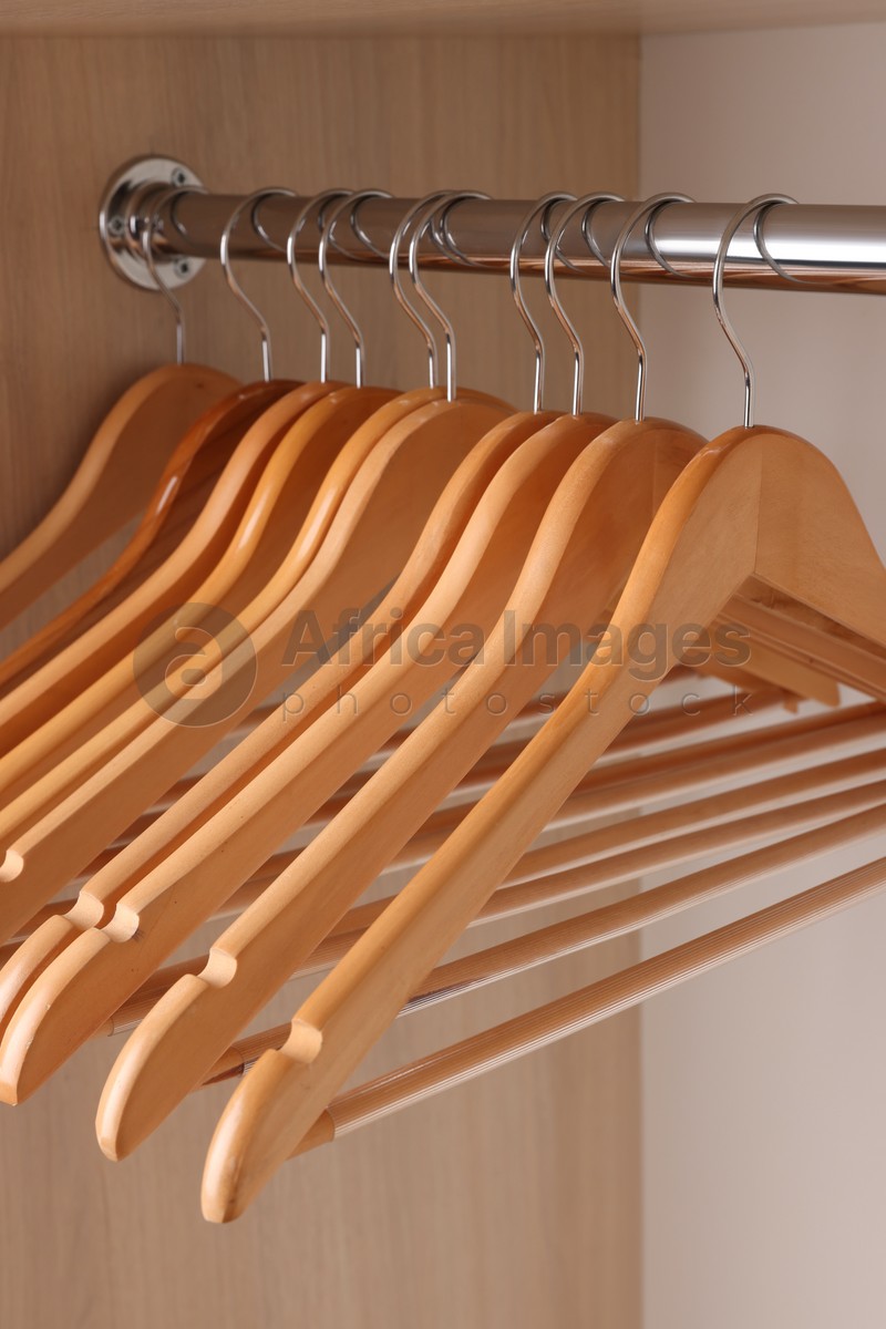 Photo of Set of clothes hangers on wardrobe rail, closeup