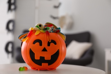 Halloween trick or treat bucket with different sweets on white table indoors