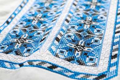 Beautiful light blue Ukrainian national embroidery on white fabric, closeup
