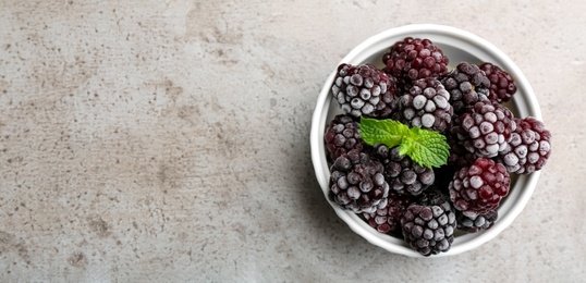 Tasty frozen blackberries with mint on grey table, top view. Space for text