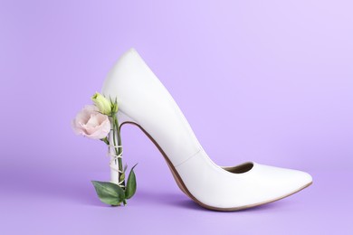 Stylish women's high heeled shoe with beautiful flower on violet background