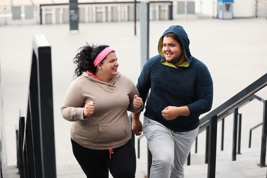 Overweight couple running up stairs together outdoors