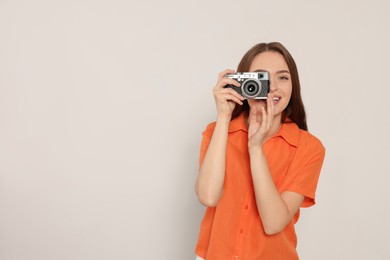 Photo of Young woman with camera taking photo on white background, space for text. Interesting hobby