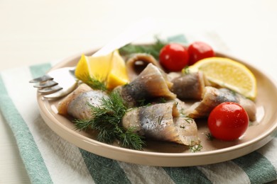 Photo of Salted herring fillets served with cherry tomatoes, dill and lemon on light beige table, closeup