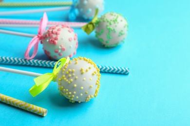 Tasty cake pops and straws on light blue background. Space for text